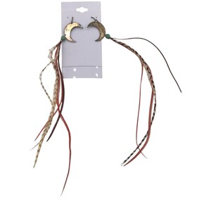 May include: A pair of crescent moon earrings featuring metallic gold-toned charms, small green beads, and long, dangling feathers in shades of brown, cream, and red, all attached to a white rectangular display card with a top hanging hole.
