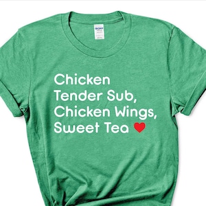 Puede incluir: Una camiseta verde con texto blanco que dice "Chicken Tender Sub, Chicken Wings, Sweet Tea" con un símbolo de corazón rojo.