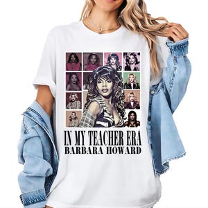 Op de afbeelding: Wit T-shirt met een afbeelding van een vrouw omringd door kleinere afbeeldingen van vrouwen. De tekst "IN MY TEACHER ERA" en "BARBARA HOWARD" staat eronder in het zwart.