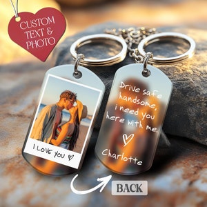 May include: Two silver-toned metal dog tag keychains with split rings. One tag features a color photograph of a couple on a beach with the text "I LOVE YOU" and a heart. The other tag displays the text "Drive safe handsome, i need you here with me." with a heart and the name "Charlotte".