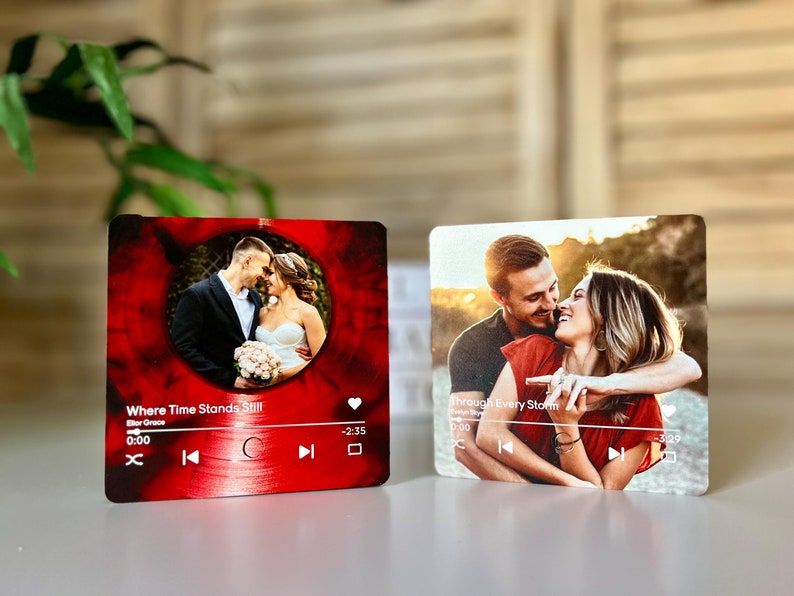 May include: Two square photo plaques. One features a couple in wedding attire, set against a red vinyl record design with the text "Where Time Stands Still". The other shows a couple embracing, with the text "Through Every Storm".