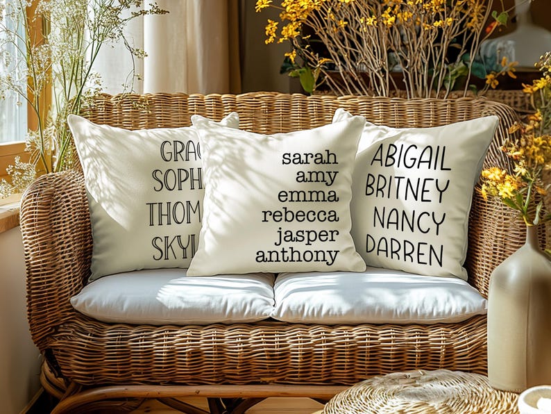 May include: Three white throw pillows with black text on a wicker couch. The pillows have the names "GRACE, SOPH, THOM, SKYL", "SARAH, AMY, EMMA, REBECCA, JASPER, ANTHONY", and "ABIGAIL, BRITNEY, NANCY, DARREN" on them.