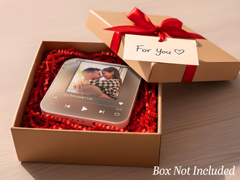 May include: A gift box with a red ribbon and a tag that says "For You". Inside, a personalized music player displays a photo of a couple. The box is filled with red paper shreds, creating a romantic presentation.