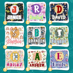 K&ouml;nnte beinhalten: Neun personalisierte Kissenbez&uuml;ge mit verschiedenen Namen und Designs. Jeder Bezug zeigt einen gro&szlig;en Anfangsbuchstaben, umgeben von einem bunten Muster. Die Namen sind James, Rachel, David, Sophia, Brandon, Taylor, Hailey, Andrew und Emily.