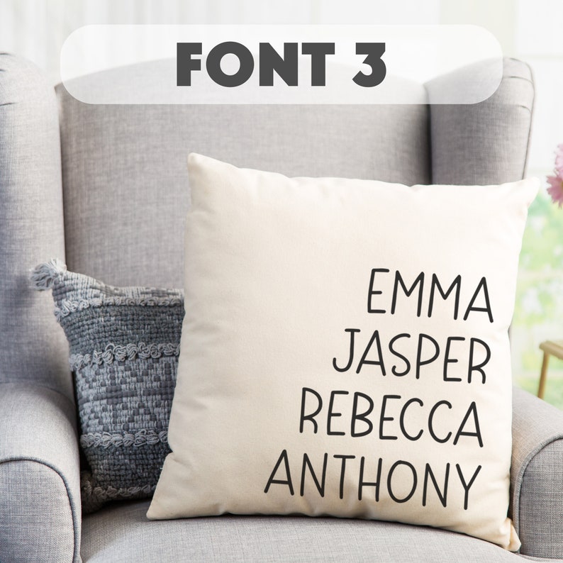 May include: A white pillow with black text that reads "Emma, Jasper, Rebecca, Anthony". The pillow is sitting on a gray armchair.