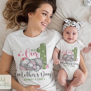 Puede incluir: Camisetas blancas y body a juego con un dise&ntilde;o para el D&iacute;a de la Madre. El dise&ntilde;o incluye el texto "Our 1st Mother's Day 2026" con un gr&aacute;fico de dos elefantes durmiendo. El body tiene una diadema de lunares a juego.