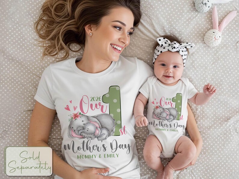 Puede incluir: Camisetas blancas y body a juego con un dise&ntilde;o para el D&iacute;a de la Madre. El dise&ntilde;o incluye el texto "Our 1st Mother's Day 2026" con un gr&aacute;fico de dos elefantes durmiendo. El body tiene una diadema de lunares a juego.