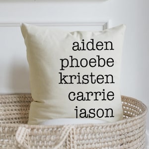 May include: White pillow with black text that reads "aiden phoebe kristen carrie jason".
