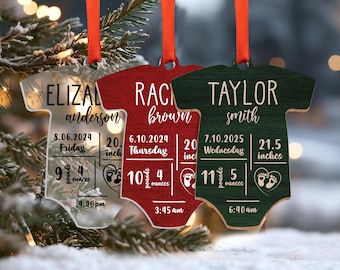 May include: Three personalized baby onesie ornaments, one clear, one red, and one green, with the names Eliza Anderson, Rachel Brown, and Taylor Smith, birth dates, weights, and lengths.