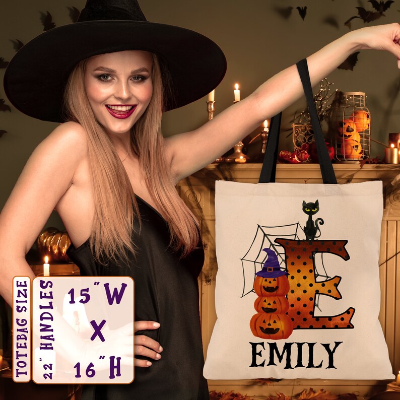 May include: A white tote bag with black handles. The bag features a black cat, a spiderweb, and a large orange letter "E" with black polka dots. The letter "E" is decorated with three orange pumpkins. The name "EMILY" is printed in black below the letter. The tote bag measures 15 inches wide by 16 inches high.