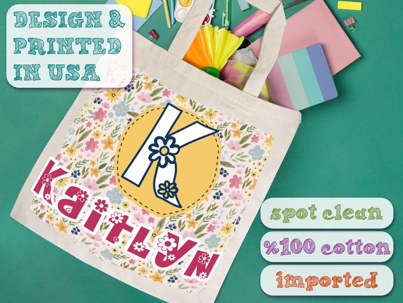 K&ouml;nnte beinhalten: Eine wei&szlig;e Canvas-Tragetasche mit einem Blumenmuster und dem Namen "Kaitlyn" in Pink bedruckt. Der Buchstabe "K" ist in einem gelben Kreis mit blauem Rand hervorgehoben. Die Tasche ist aus 100% Baumwolle und importiert. Nur Fleckenreinigung.