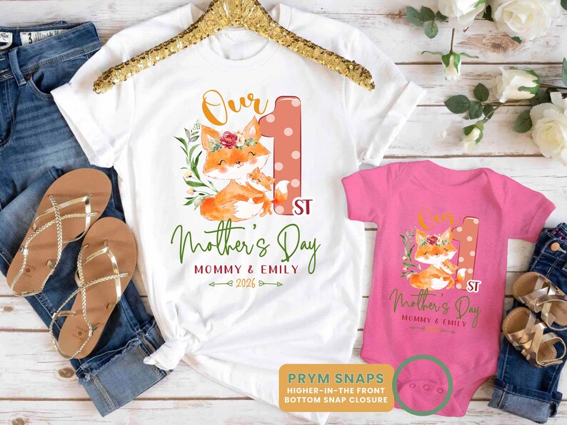 Puede incluir: Camiseta blanca y body rosa con un gr&aacute;fico de zorro a juego y texto para el D&iacute;a de la Madre. La camiseta y el body tienen el texto "Our 1st Mother's Day" y "Mommy & Emily 2026". El body tiene cierres de presi&oacute;n.