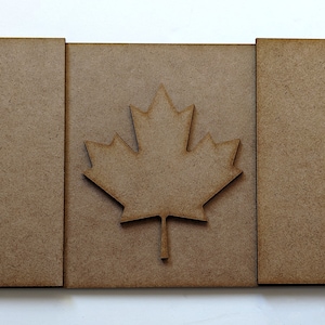 May include: A wooden cutout of the Canadian flag, featuring a red maple leaf on a white background with red borders.
