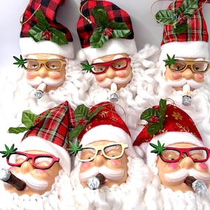 May include: Six Santa Claus ornaments with red and black plaid hats, each wearing glasses and smoking a cigar. The ornaments have white beards and are decorated with green leaves and red berries. The glasses are in various colors.