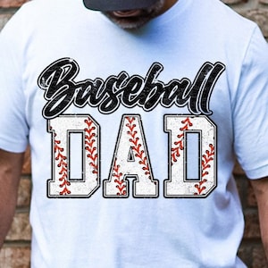 Puede incluir: Camiseta blanca con un gráfico de béisbol negro y rojo y el texto "Baseball Dad".