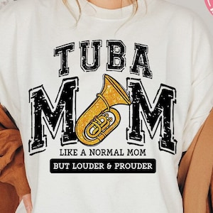 Könnte beinhalten: Weißes Sweatshirt mit schwarzem Text, der "TUBA MOM LIKE A NORMAL MOM BUT LOUDER & PROUDER" lautet. In der Mitte des Textes befindet sich eine goldene Tuba.