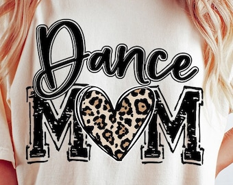 May include: A white t-shirt with the text "Dance Mom" in black with a leopard print heart in the middle of the word "Mom". The shirt is being worn by a person with long blonde hair. The text "Digital Download PNG only" is in a pink circle with a white outline.