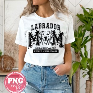 May include: White t-shirt with black text that reads "Labrador Mom Like a Normal Mom Except Much Cooler". A black and white illustration of a Labrador Retriever is in the centre of the text.