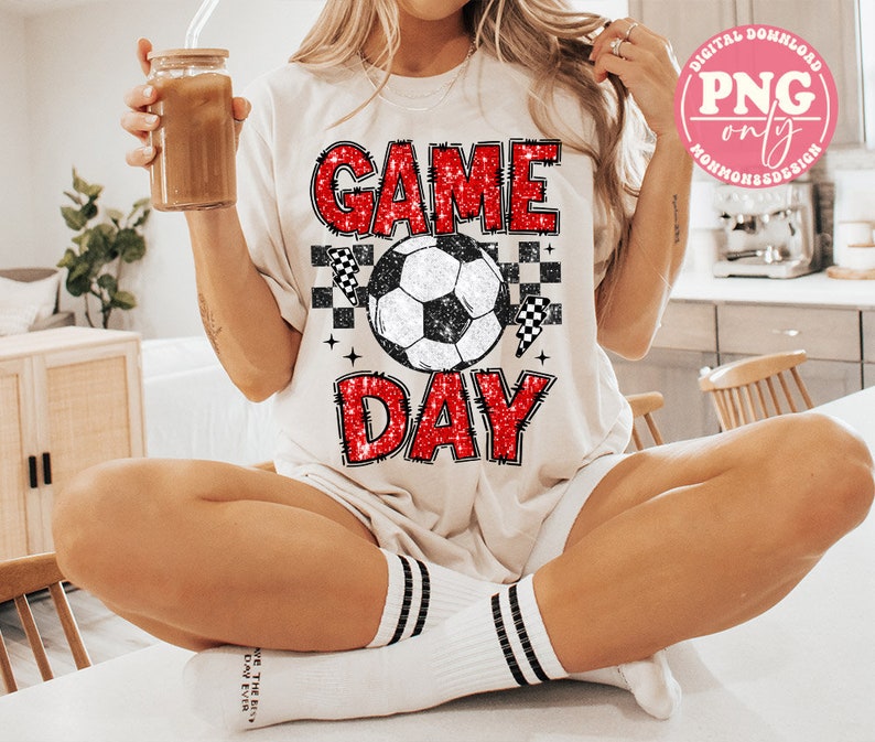 May include: A white t-shirt with red glitter text that says "GAME DAY" and a black and white soccer ball graphic.