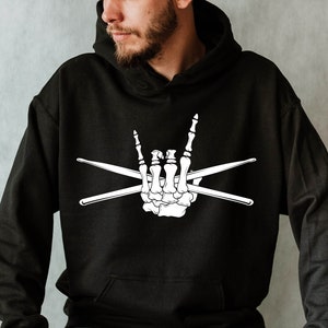 May include: A black hoodie with a white skeleton hand making the rock and roll hand gesture with two crossed drumsticks.