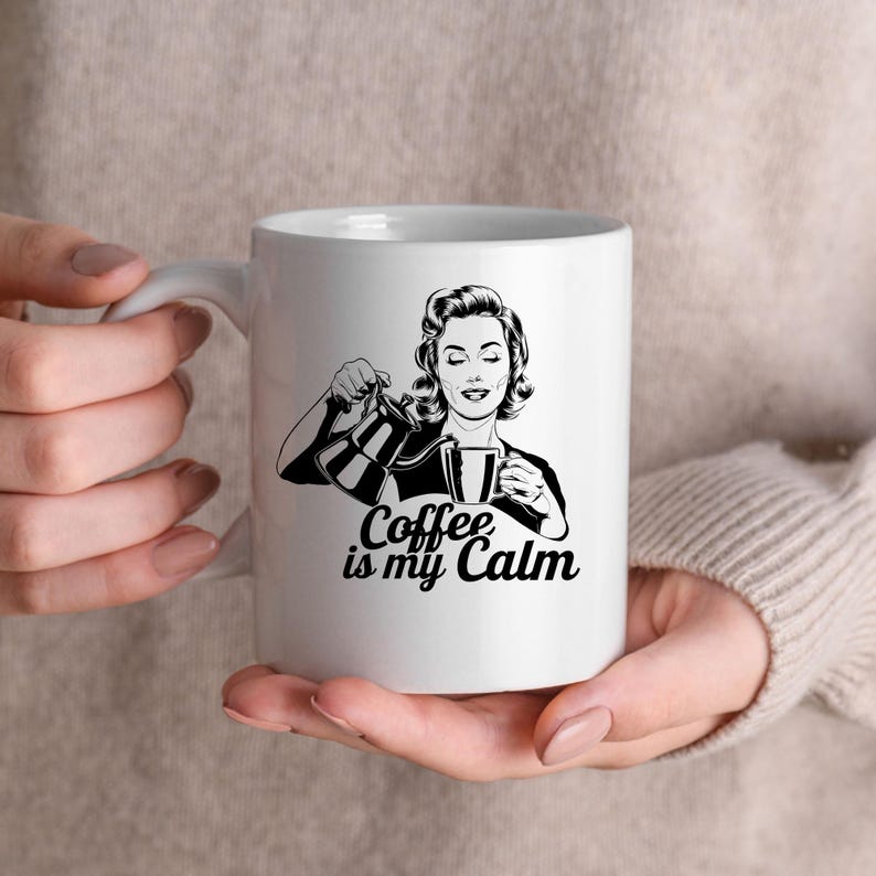 May include: White ceramic mug with a black and white illustration of a woman pouring coffee. The text "Coffee is my Calm" is printed on the mug.