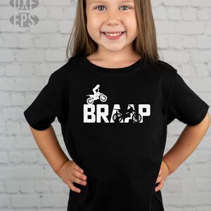 Op de afbeelding: Een jong persoon draagt een zwart T-shirt met een witte afbeelding van een crossmotor en het woord "BRAAP".