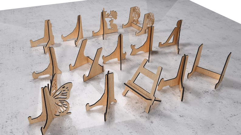 May include: A collection of wooden display stands in various designs. Some stands feature decorative cutouts, including a butterfly, a floral pattern, and a deer. The stands are made of light-colored wood with dark edges.