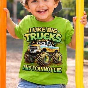 May include: A young child wearing a green t-shirt with the text "I Like Big Trucks And I Cannot Lie" and a cartoon monster truck graphic. The child is also wearing a gray baseball cap and blue denim shorts.