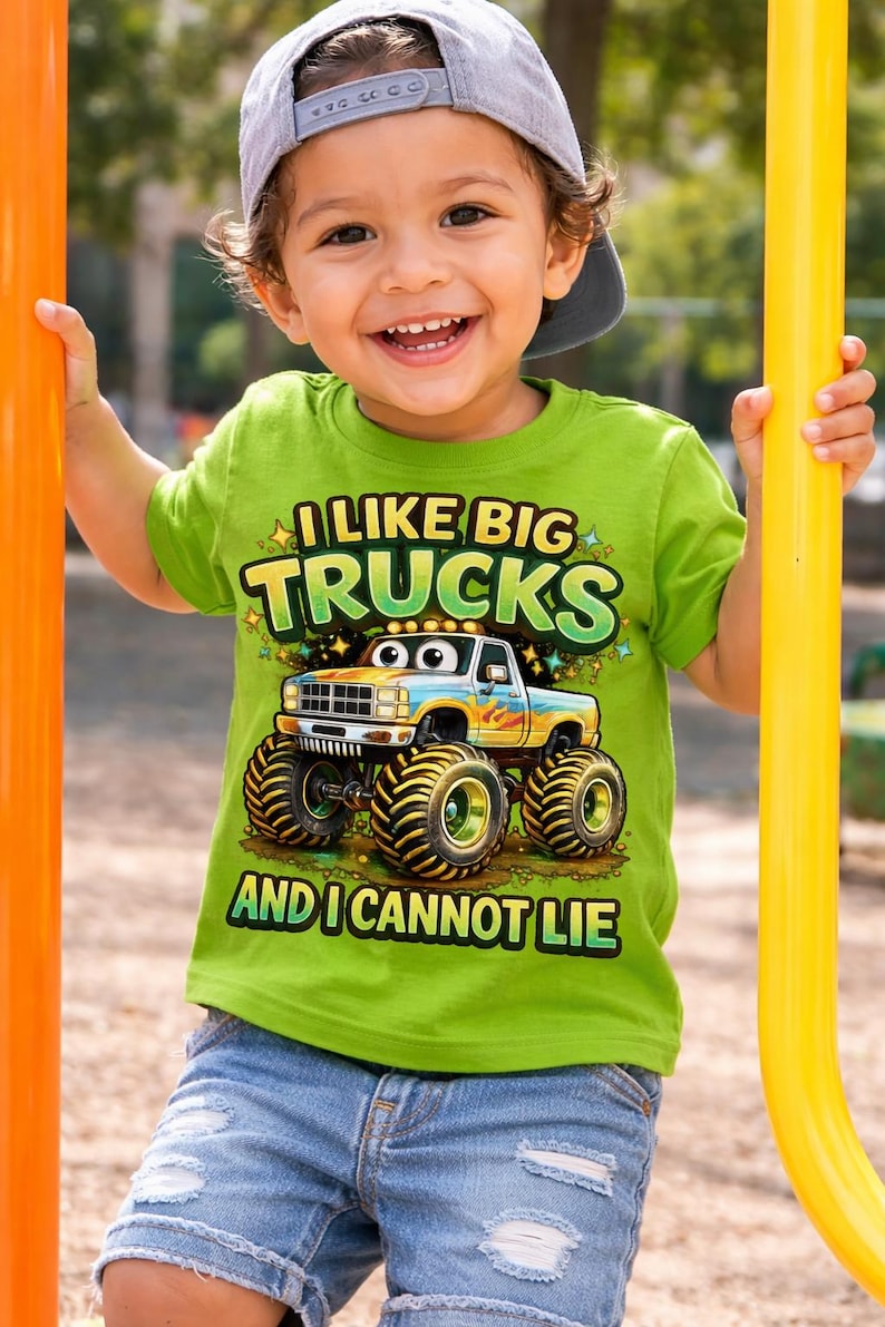 May include: A young child wearing a green t-shirt with the text "I Like Big Trucks And I Cannot Lie" and a cartoon monster truck graphic. The child is also wearing a gray baseball cap and blue denim shorts.