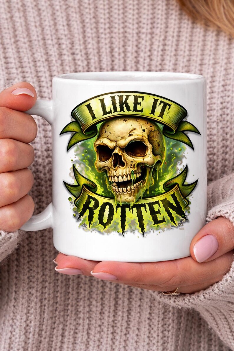 May include: White ceramic mug featuring a detailed illustration of a skull with the text "I LIKE IT ROTTEN" in a green banner. The skull has a decaying appearance with green accents, creating a spooky aesthetic.