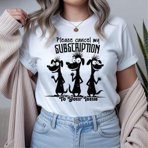 Może przedstawiać: Biała koszulka z napisem "Please cancel my subscription To Your Issue" nad grafiką trzech czarnych ps&oacute;w z kresk&oacute;wek. Psy machają i uśmiechają się. Koszulka jest w stylu casual.