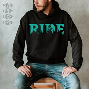 Pode incluir: Um moletom preto com um gráfico azul turquesa de uma pessoa andando de bicicleta por uma floresta com a palavra "RIDE" acima do gráfico.