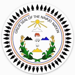 Op de afbeelding: Het Grote Zegel van de Navajo-natie heeft een witte achtergrond met een rode, gele en blauwe cirkel rond de buitenrand. Binnen de cirkel bevinden zich een zon met stralen, bergen, een paard, een schaap, een ram en een plant met gele bloemen. De tekst "Great Seal of the Navajo Nation" staat in een cirkel rond het midden van het zegel.