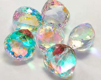 Puede incluir: Un conjunto de seis piedras de vidrio transparente en forma de lágrima, con facetas y acabado iridiscente. Cada piedra muestra un espectro de colores arcoíris, incluyendo azul, verde, rosa y amarillo, reflejando la luz a través de sus superficies geométricas.