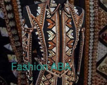 Könnte beinhalten: Eine schwarze Showjacke mit einem geometrischen Muster in Braun, Weiß und Gold. Die Jacke ist mit Strasssteinen und Perlen verziert. Der Text "Fashion ABA" ist auf der Jacke sichtbar.