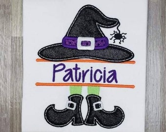 May include: A white t-shirt with an embroidered witch design. The witch has a black hat with a purple band, green legs, and black shoes. The name "Patricia" is embroidered in purple on a banner above the witch's legs.