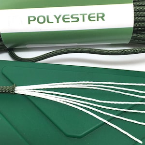 May include: A coil of dark olive green cord wrapped in a white paper label with the word POLYESTER printed in green. The cord is frayed at one end, revealing seven thin white inner strands extending outward over a dark green plastic surface.