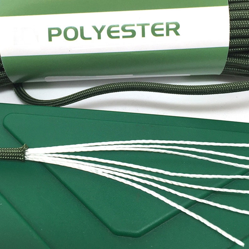 May include: A coil of dark olive green cord wrapped in a white paper label with the word POLYESTER printed in green. The cord is frayed at one end, revealing seven thin white inner strands extending outward over a dark green plastic surface.