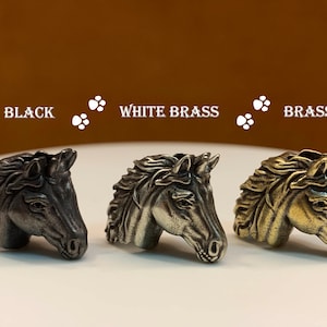 May include: Three horse head figurines in different finishes: black, white brass, and brass. The figurines are detailed and have a realistic look.