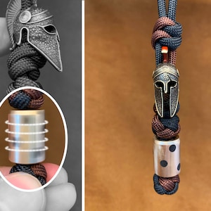 May include: A black and brown paracord bracelet with a silver and gold metal bead and a silver Spartan helmet charm.