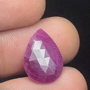 Puede incluir: Una piedra preciosa de rubí rosa facetada en forma de pera.