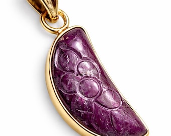 Könnte beinhalten: Goldener Anhänger mit einem halbmondförmigen, geschnitzten lila Edelstein. Der Edelstein weist ein Blumenmuster auf und ist in einen goldenen Rahmen gefasst. Der Anhänger hat eine goldene Öse für eine Kette.