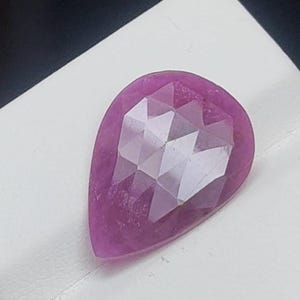 Puede incluir: Una piedra preciosa rosa en forma de pera con un corte facetado.