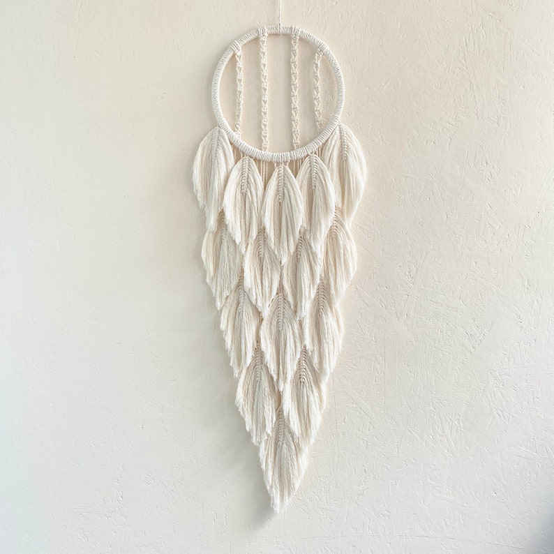 May include: A white macrame wall hanging with a circular top and a cascading design of fringe tassels.