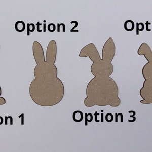 May include: Four different wooden bunny cutout options for crafts. The bunny cutouts are all brown and have different shapes and sizes. Option 1 has a tail, option 2 is round, option 3 has a long ear, and option 4 is a simple bunny shape.