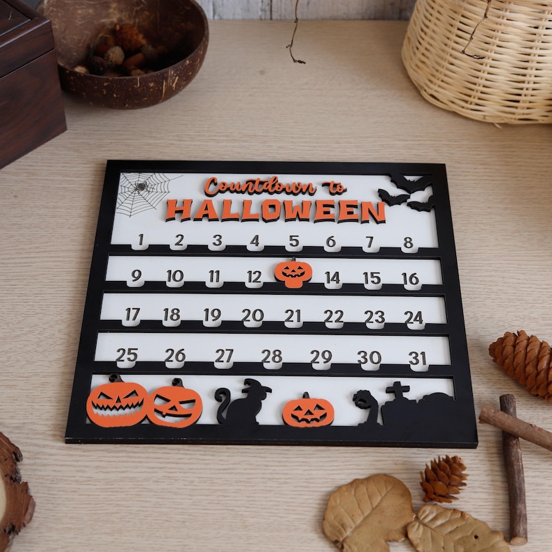 May include: A black and white Halloween countdown calendar with the words "Countdown to Halloween" in orange. The calendar features numbers 1-31, pumpkins, bats, a spider web, a black cat, and a tombstone.