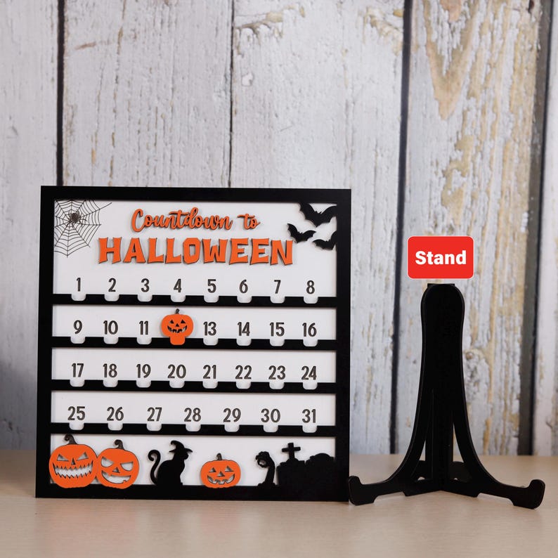May include: Black and white Halloween countdown calendar with orange accents. Features the text "Countdown to Halloween", numbers 1-31, pumpkins, bats, and a spiderweb. Includes a black stand.