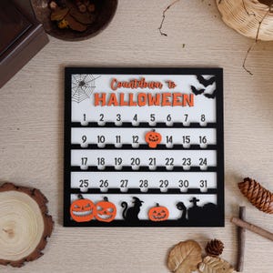 May include: A black and white Halloween countdown calendar with orange accents. The calendar features the text "Countdown to Halloween" and numbers 1-31. Decorative pumpkins, bats, and a black cat are also included.