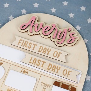 May include: A wooden sign with the name "Avery's" in pink lettering. The sign includes the phrases "FIRST DAY OF" and "LAST DAY OF" in a banner design, with space for additional information.