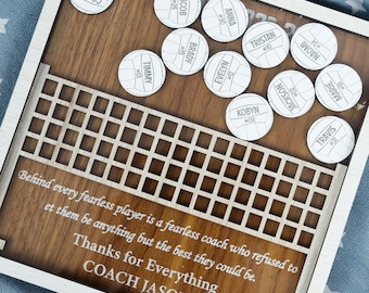 May include: A wooden volleyball net frame with a quote about coaches and players. The frame is decorated with white volleyball-shaped tokens with names and numbers on them. The quote reads: "Behind every fearless player is a fearless coach who refused to let them be anything but the best they could be. Thanks for Everything COACH JASON"